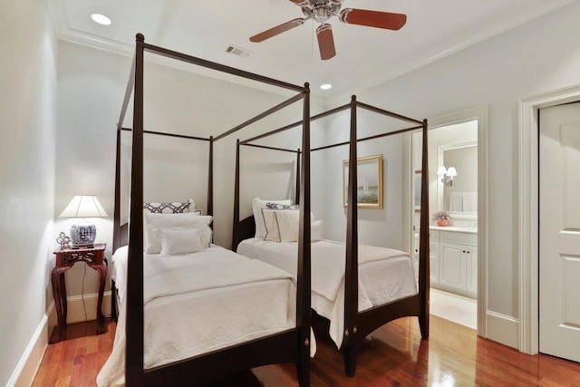 bedroom with crown molding, ensuite bath, ceiling fan with notable chandelier, and light hardwood / wood-style flooring