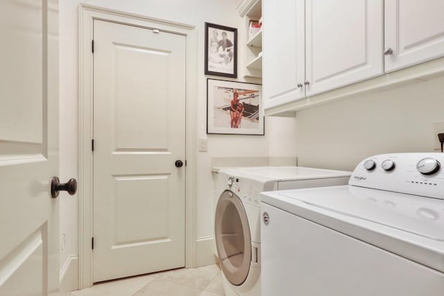 laundry area featuring cabinets, light tile floors, and washer and dryer