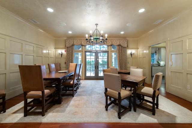 dining room with light wood-type flooring, french doors, crown molding, and a chandelier