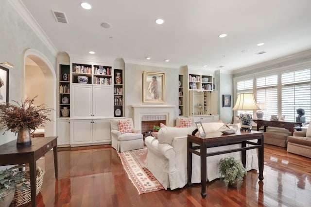 living room featuring dark hardwood / wood-style flooring, built in features, and ornamental molding