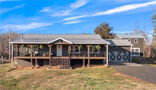 view of front facade with metal roof, covered porch, an outdoor structure, driveway, and a front yard