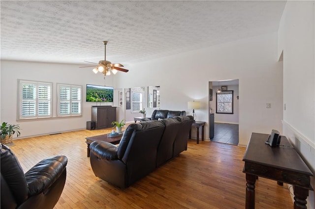 living room featuring a textured ceiling, hardwood / wood-style floors, vaulted ceiling, and a healthy amount of sunlight