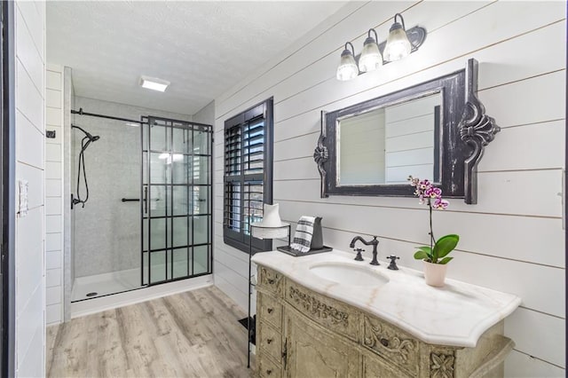 full bath with a textured ceiling, a stall shower, wood finished floors, and vanity