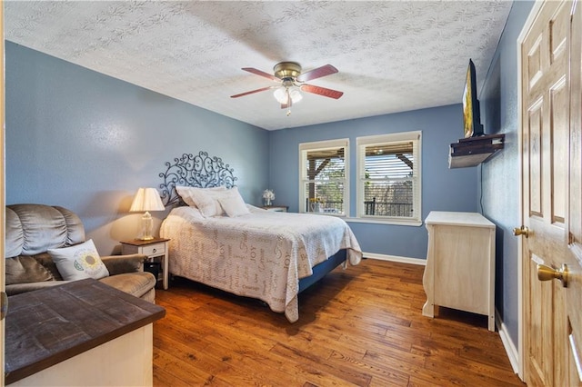 bedroom featuring wood-type flooring, baseboards, ceiling fan, and a textured ceiling