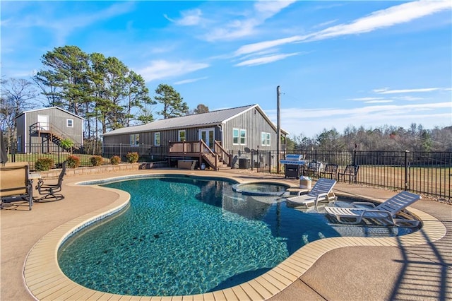 view of pool with fence, a pool with connected hot tub, stairs, a wooden deck, and a patio area