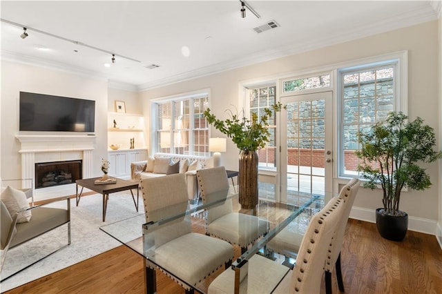 dining room featuring wood-type flooring, track lighting, and ornamental molding