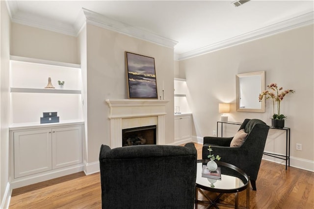 living room with light wood-type flooring, crown molding, and built in features