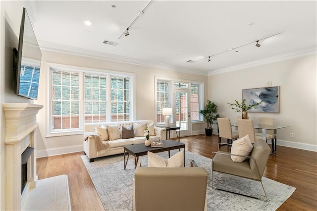 living room featuring light hardwood / wood-style flooring, track lighting, and ornamental molding