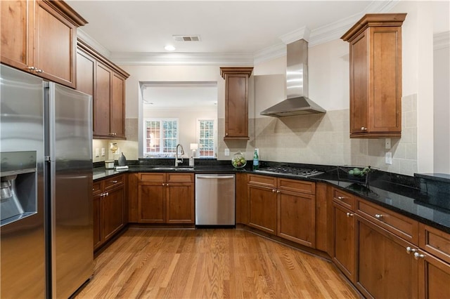 kitchen with dark stone countertops, light hardwood / wood-style floors, sink, stainless steel appliances, and wall chimney exhaust hood