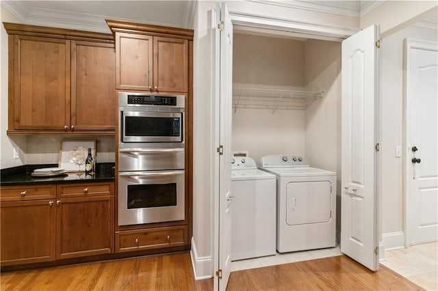 clothes washing area with crown molding, separate washer and dryer, and light hardwood / wood-style floors