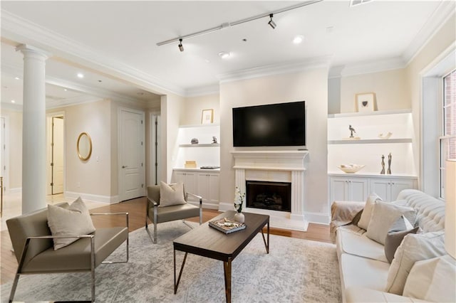 living room featuring ornate columns, ornamental molding, rail lighting, and light hardwood / wood-style flooring