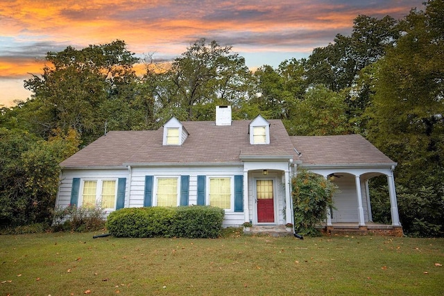 new england style home featuring a chimney and a front lawn