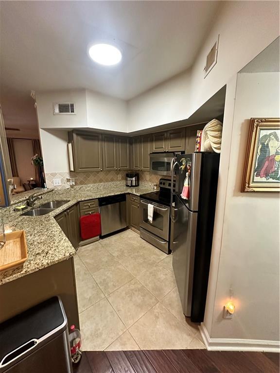 200 Renaissance Pkwy NE Unit 305, Atlanta, GA 30308 - kitchen featuring stainless steel appliances, a sink, light stone countertops, tasteful backsplash, and light tile patterned floors