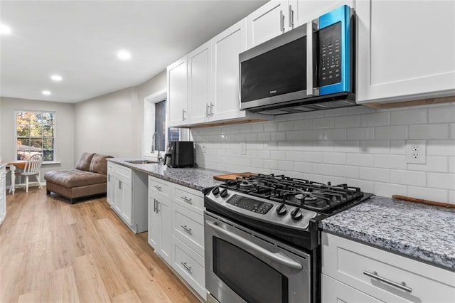 kitchen with white cabinetry, stainless steel appliances, and light stone countertops