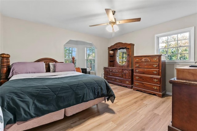 bedroom featuring ceiling fan, light hardwood / wood-style floors, and multiple windows