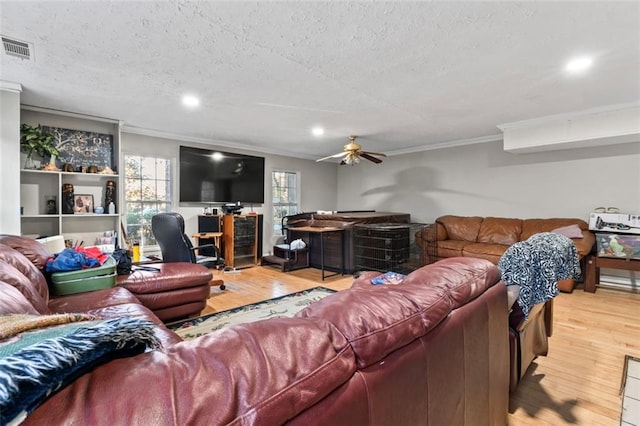 living room with ceiling fan, ornamental molding, light hardwood / wood-style floors, and a textured ceiling