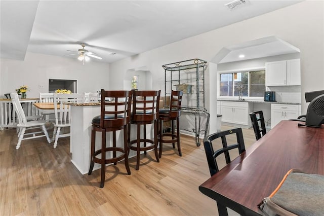 kitchen with light wood-type flooring, white cabinets, and light stone counters