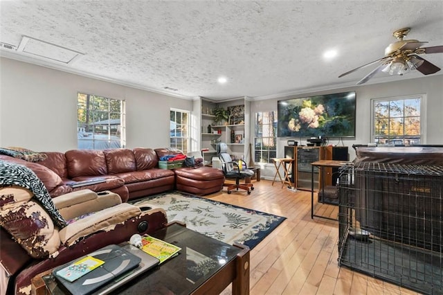 living room with ceiling fan, ornamental molding, light hardwood / wood-style floors, and a textured ceiling