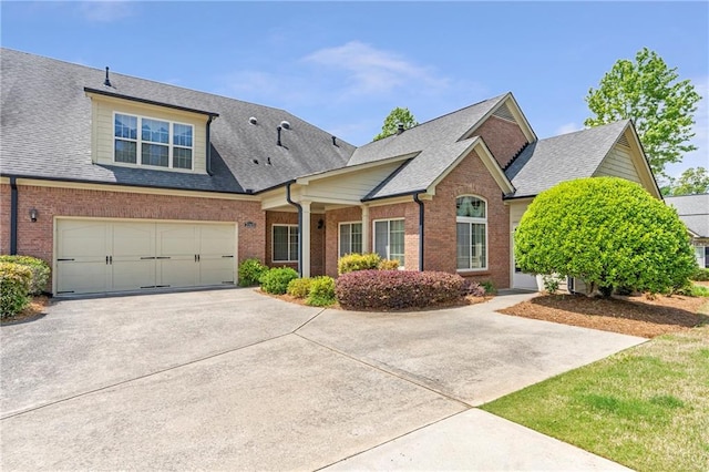 view of front of house featuring an attached garage, a shingled roof, concrete driveway, and brick siding