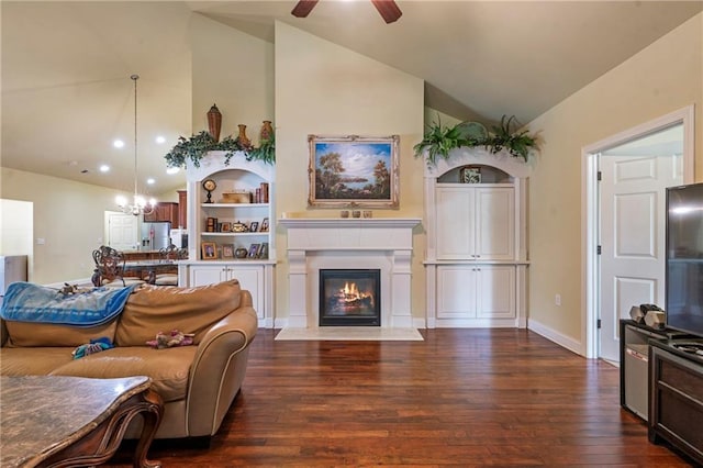 living area featuring dark wood-style flooring, baseboards, high vaulted ceiling, a fireplace with flush hearth, and ceiling fan with notable chandelier