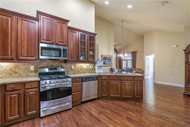 kitchen with appliances with stainless steel finishes, high vaulted ceiling, a peninsula, tasteful backsplash, and dark wood-type flooring