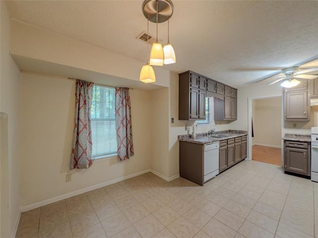 kitchen with white dishwasher, ceiling fan, light tile patterned flooring, baseboards, and a textured ceiling