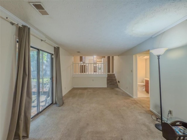 spare room with light carpet, a textured ceiling, baseboards, and stairway