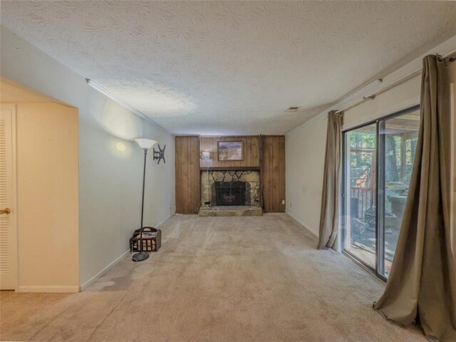 unfurnished living room featuring carpet floors, a fireplace, a textured ceiling, baseboards, and crown molding