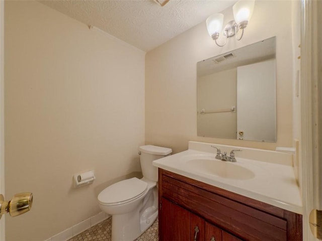 half bathroom featuring toilet, a textured ceiling, vanity, tile patterned floors, and baseboards