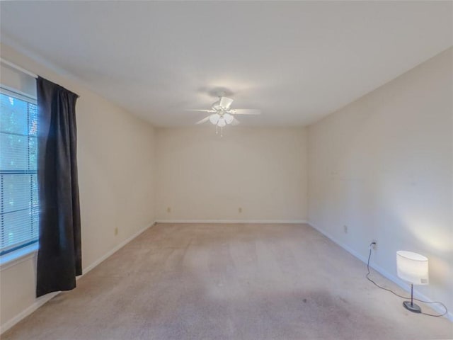empty room with a ceiling fan, light colored carpet, and baseboards