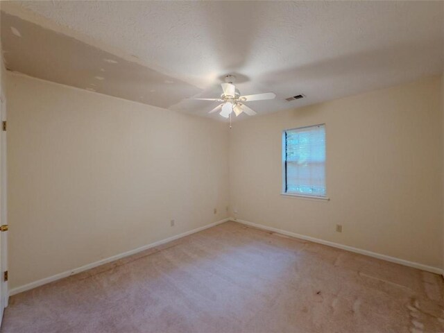 empty room with ceiling fan, light carpet, baseboards, and a textured ceiling