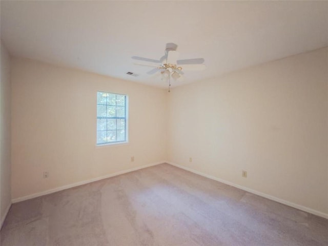 spare room featuring light carpet, baseboards, and a ceiling fan