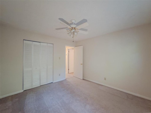 unfurnished bedroom featuring light colored carpet, baseboards, a closet, and ceiling fan