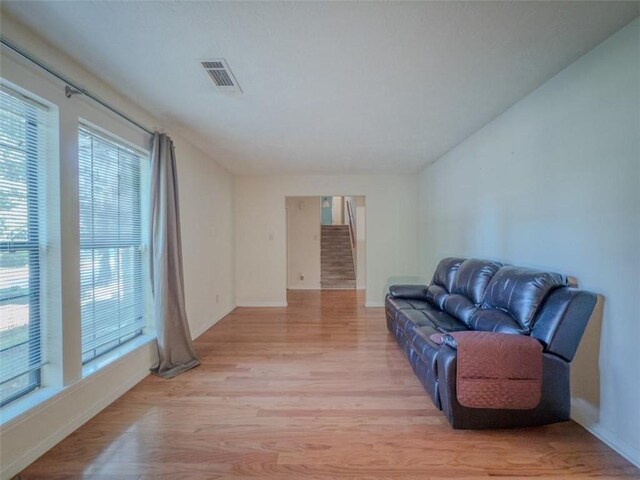 living area with light wood-style floors, baseboards, and stairs