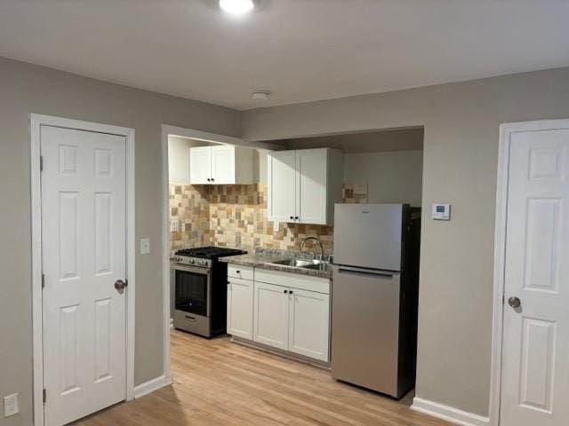 kitchen featuring white cabinetry, stainless steel range with gas cooktop, light hardwood / wood-style floors, and fridge