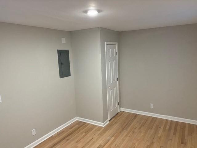 spare room featuring electric panel and light wood-type flooring