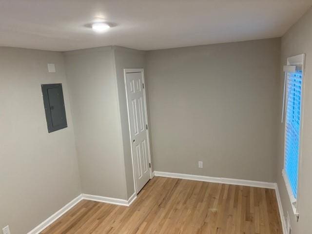 spare room with electric panel and light hardwood / wood-style floors