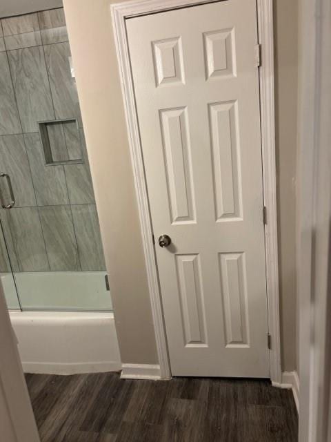 bathroom featuring hardwood / wood-style floors and combined bath / shower with glass door