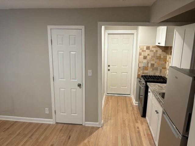 kitchen featuring light stone countertops, white cabinetry, light wood-type flooring, and appliances with stainless steel finishes