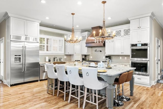 4670 Hamden Forest Dr SW, Atlanta, GA 30331 - kitchen featuring appliances with stainless steel finishes, a chandelier, island exhaust hood, tasteful backsplash, and white cabinetry