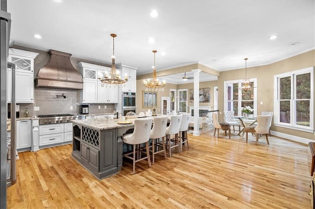 4670 Hamden Forest Dr SW, Atlanta, GA 30331 - kitchen with a chandelier, custom range hood, appliances with stainless steel finishes, light wood finished floors, and crown molding