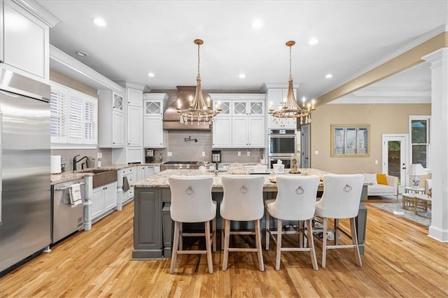 4670 Hamden Forest Dr SW, Atlanta, GA 30331 - kitchen featuring stainless steel appliances, a chandelier, decorative backsplash, an island with sink, and glass insert cabinets