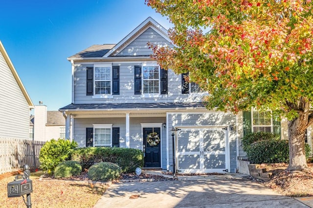 view of front of property featuring concrete driveway, fence, and an attached garage