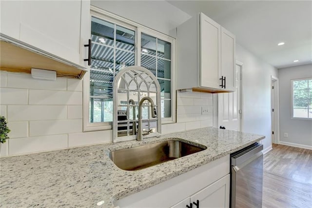 3991 Adamsville Dr SW, Atlanta, GA 30331 - kitchen with stainless steel dishwasher, backsplash, white cabinetry, light wood-style floors, and light stone counters
