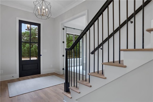 foyer with an inviting chandelier, ornamental molding, and light hardwood / wood-style flooring