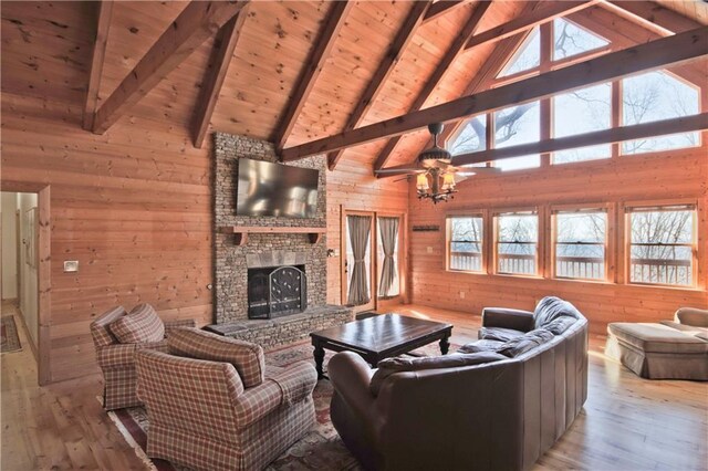 living room featuring light wood-type flooring, ceiling fan, wooden walls, wooden ceiling, and beamed ceiling