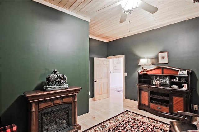 interior space with a fireplace, a ceiling fan, wood finished floors, wooden ceiling, and baseboards