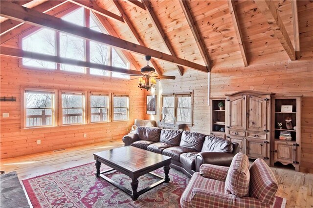 living room featuring wood ceiling, beamed ceiling, light hardwood / wood-style floors, a stone fireplace, and wood walls