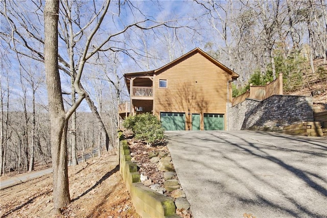 view of property exterior featuring a garage, driveway, and a balcony