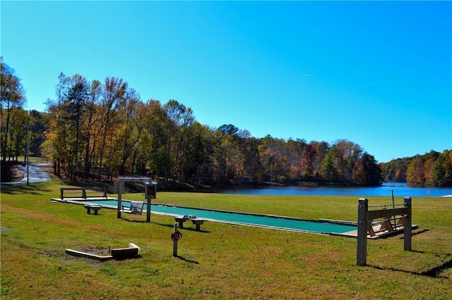 view of property's community featuring a yard, a water view, and a wooded view